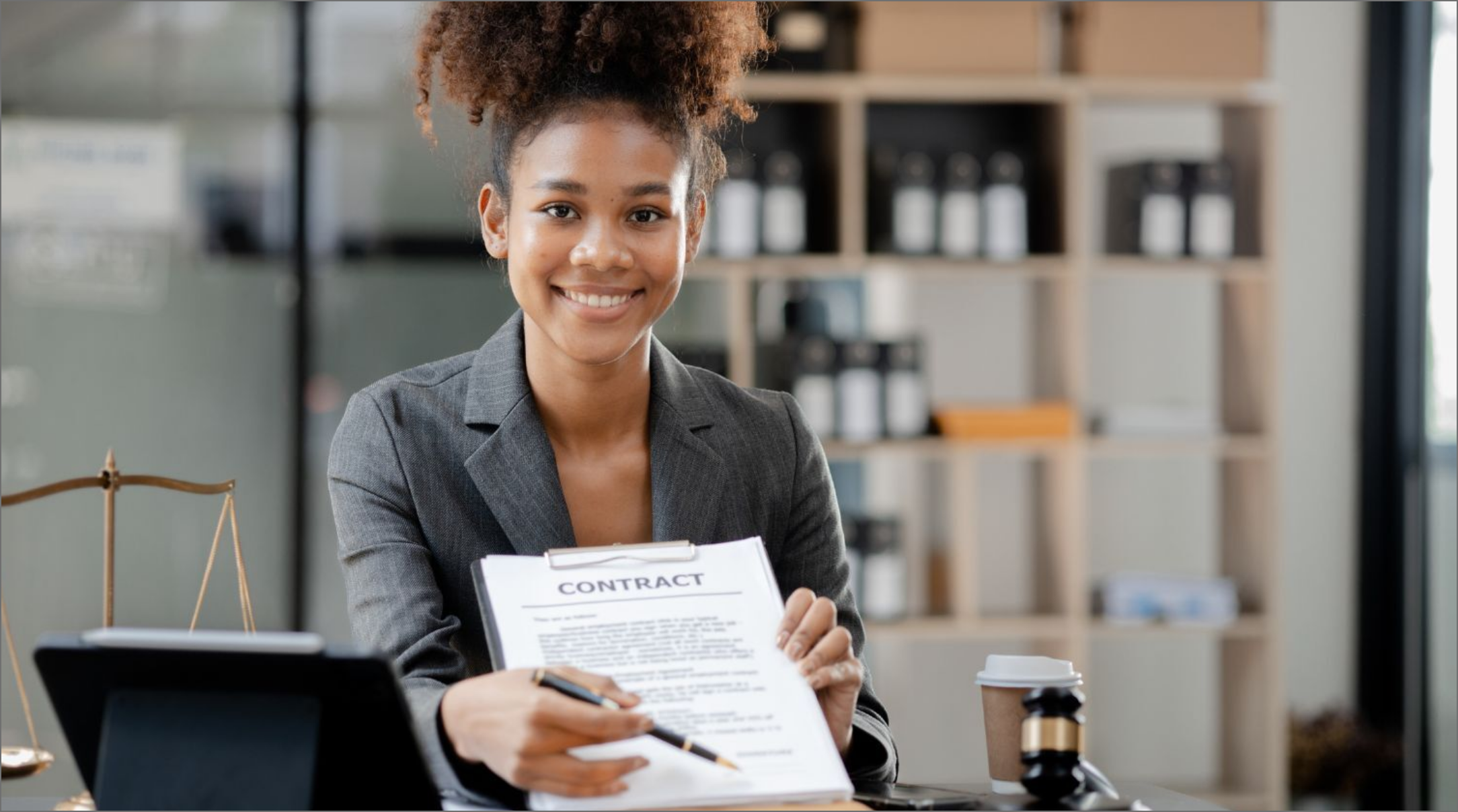 A lawyer smiling and holding up a contract with a pen