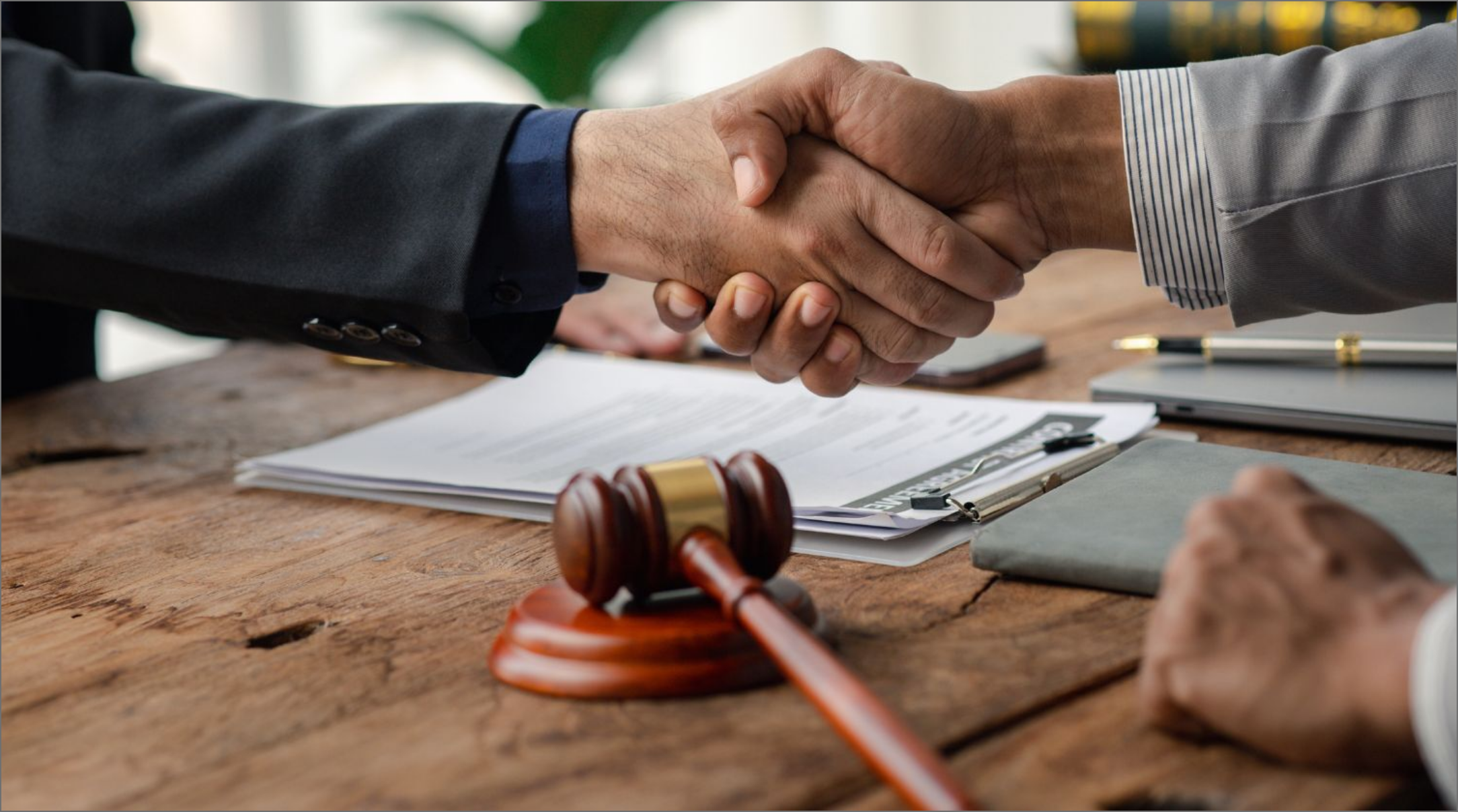 Two lawyers sitting opposite each other shaking hands